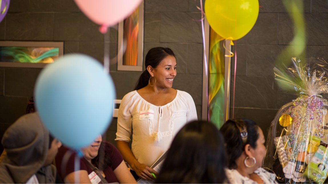 Pregnant Latina woman surrounded by balloons at maternity event