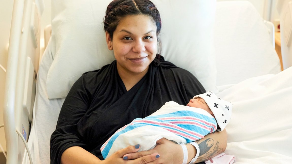 Young Latina mother holding newborn baby