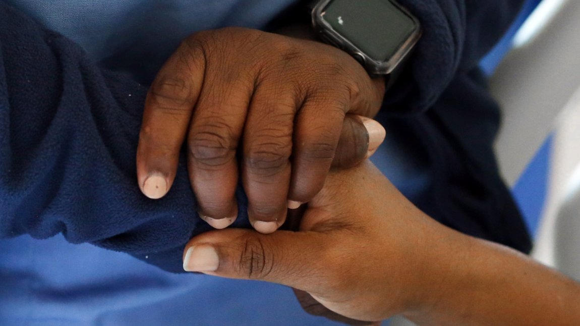 Close up of black nurse holding patient's hand