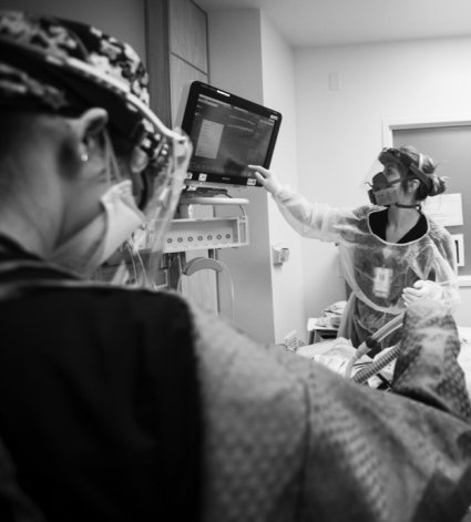 Fotografía en blanco y negro de enfermeras usando un equipo de protección personal en una sala del hospital