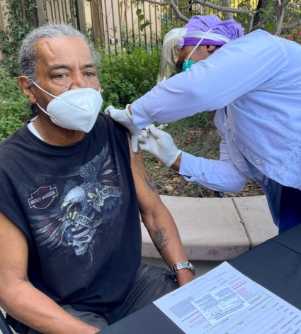 Un hombre mayor de color recibe una vacuna de una enfermera de color
