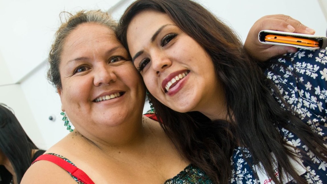 Latina mother and daughter smiling with heads close